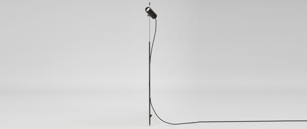 Proyector de pie para exterior IP65 con opción simple o doble, diseñado por el arquitecto francés Jean-Michel Wilmotte. Una pieza de iluminación exterior exclusiva pensada para proyectos donde la estética, la resistencia y el rendimiento técnico son esenciales. Este foco LED de diseño cuenta con estaca de acero inoxidable AISI 316 para instalación directa a tierra. Su cuerpo, fabricado en aluminio mecanizado con anillo frontal y tapa posterior en anodizado negro mate, combina elegancia y durabilidad. Funciona con bombillas GU10 LED reemplazables, lo que permite ajustar temperatura de color, apertura y potencia en función del proyecto. Ideal para iluminar exteriores con personalidad, en espacios residenciales, comerciales o institucionales de alto nivel. Premium outdoor spotlight with ground spike, designed by renowned French architect and lighting designer Jean-Michel Wilmotte. Available in single or double spotlight versions, this IP65-rated luminaire is perfect for high-end landscape architecture, garden lighting, and designer outdoor environments. Crafted from high-precision machined aluminum, with a matte black anodized front ring and back cap, this exterior spotlight features a ground stake made of AISI 316 stainless steel for direct soil installation. The fixture is compatible with replaceable GU10 LED bulbs, offering flexibility in beam angle, power, and color temperature. Ideal for projects that require exclusive exterior lighting, architectural precision, and a refined minimalist aesthetic.